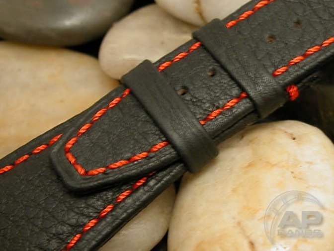 Black leather watch strap with red stitching.
