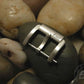 A brushed metal AP Bands watch buckle rests on a smooth, dark stone. 
