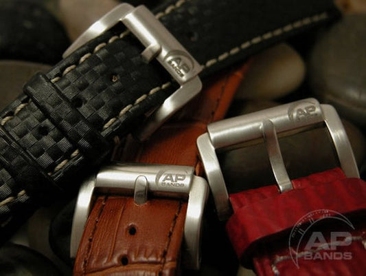 Three watch straps with contrasting styles: black checkered leather, brown alligator grain, and red textured leather, each showcasing a polished metal "AP Bands" buckle. 
